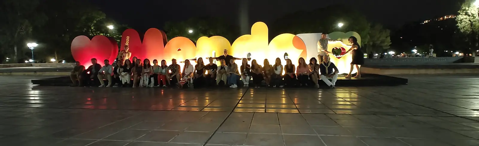 Foto de grupo de noche frente a las letras iluminadas de Mendoza